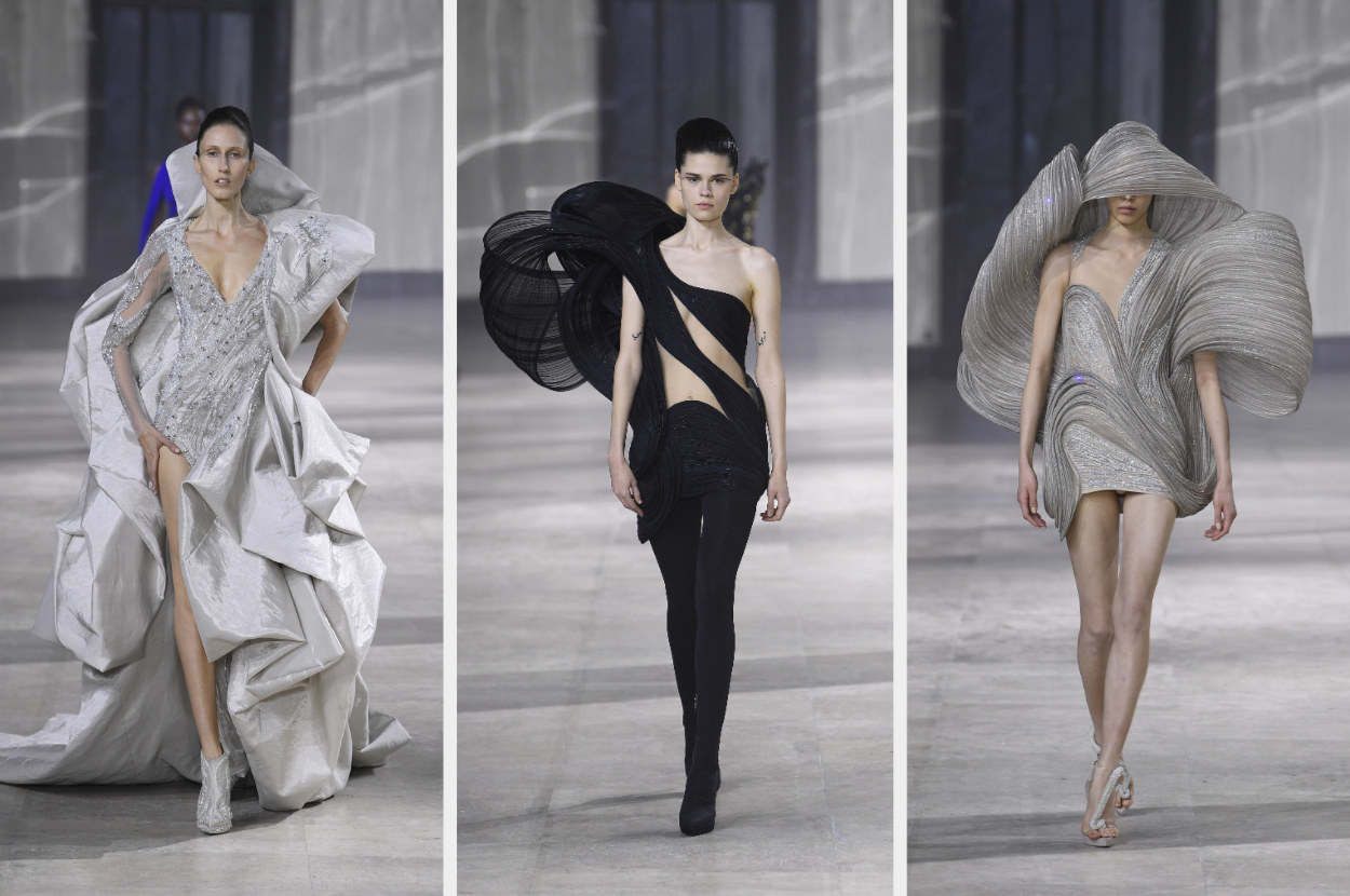 Left,: a model wears a voluminous layered gown with a high back. The model in the middle&#x27;s wearing an architectural jumpsuit with a shoulder piece that juts out. On the right, the model&#x27;s wearing a short dress that has an architectural shoulder piece/hood