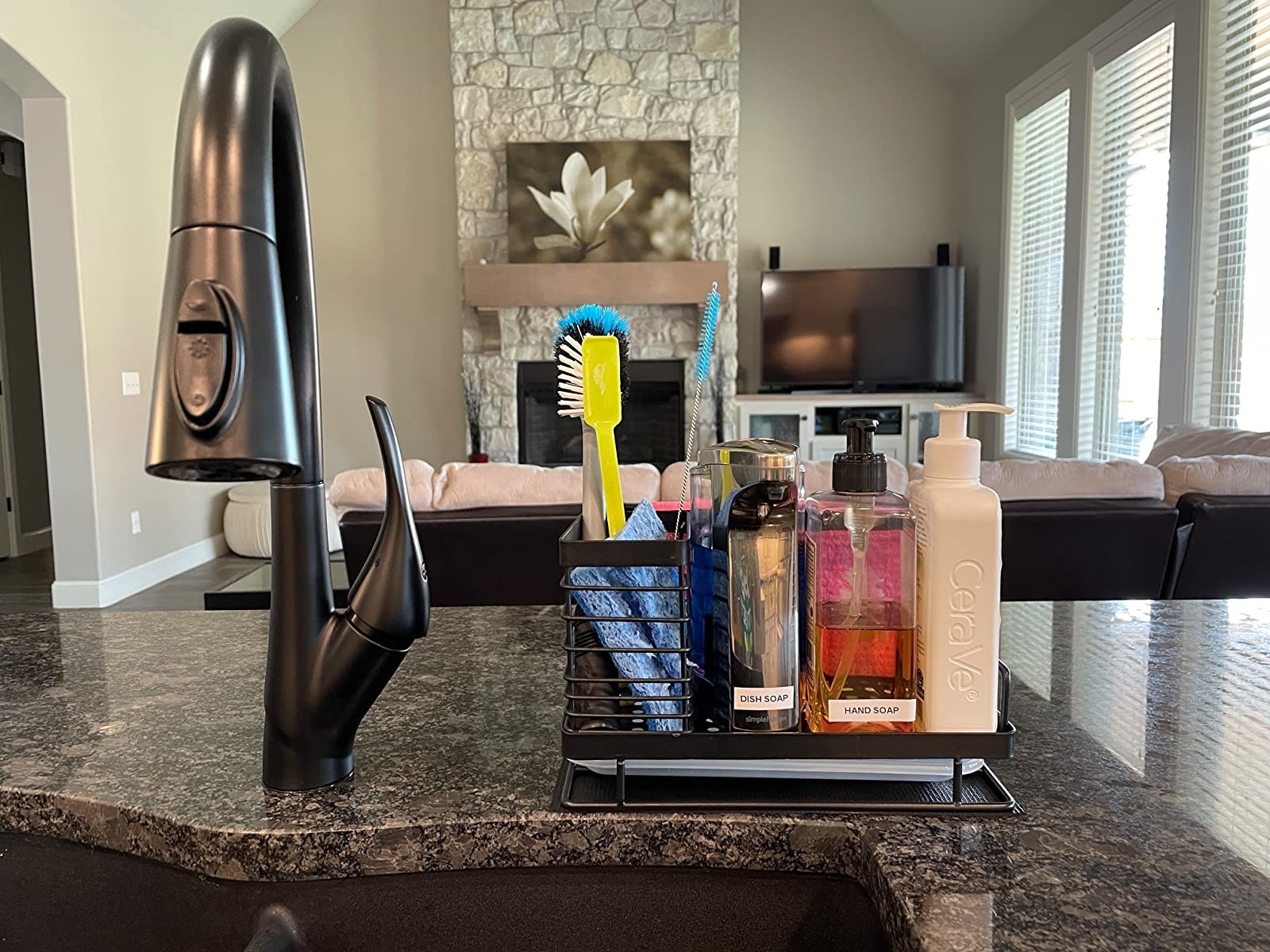 reviewer photo of the black sink organizer next to faucet filled with soap, sponges, etc.