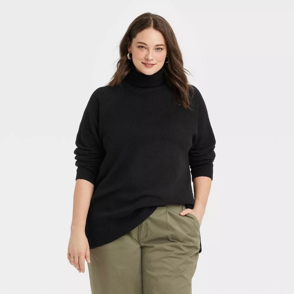 The model wearing the black tunic turtleneck with green pants
