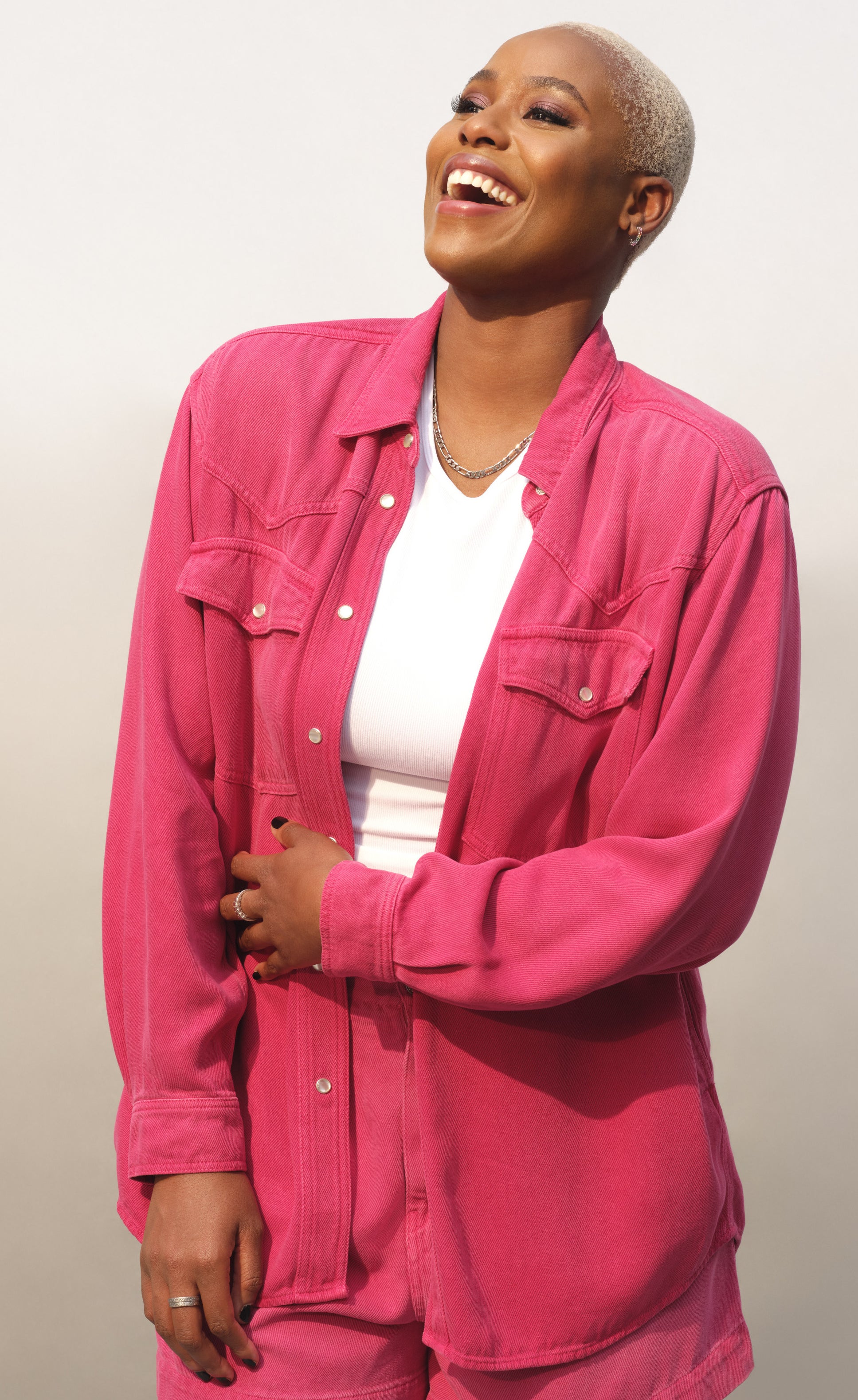 Jerrie Johnson poses, smiling, in a pink shirt and shorts
