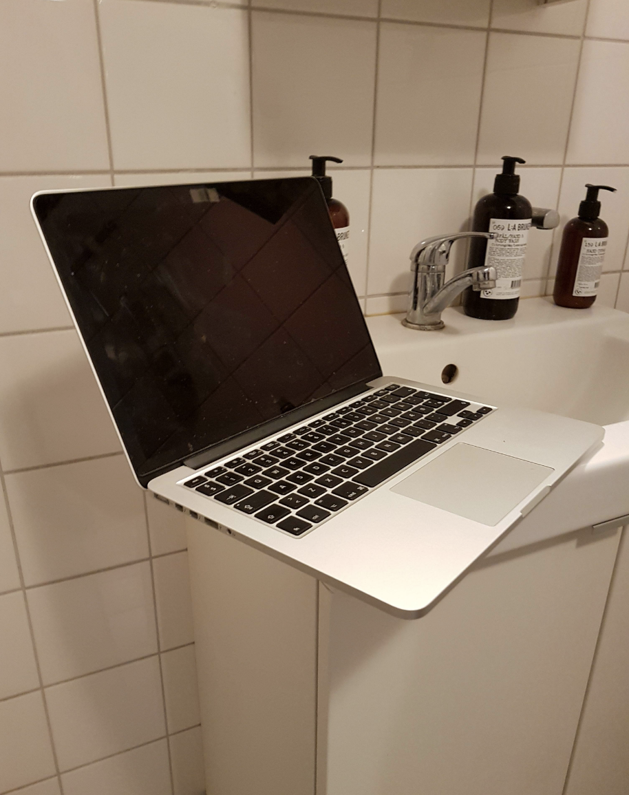 A laptop on a bathroom counter