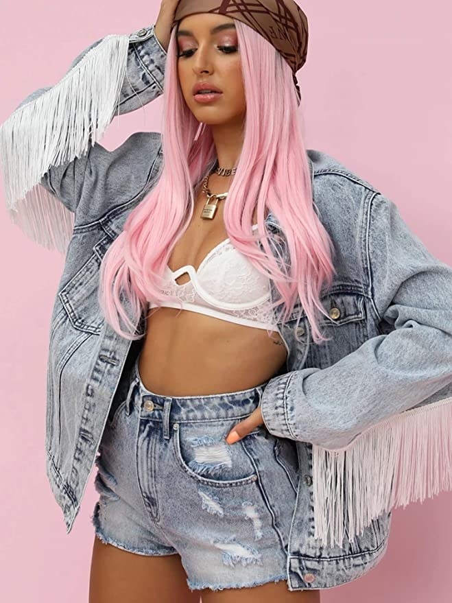 a person wearing the fringed denim jacket with a bra and matching denim shorts