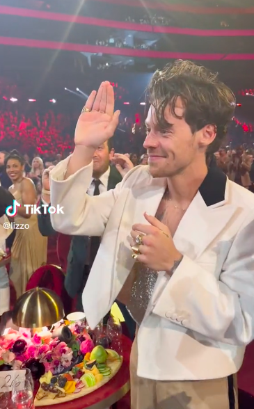 Harry waving as he stands at his table in the audience