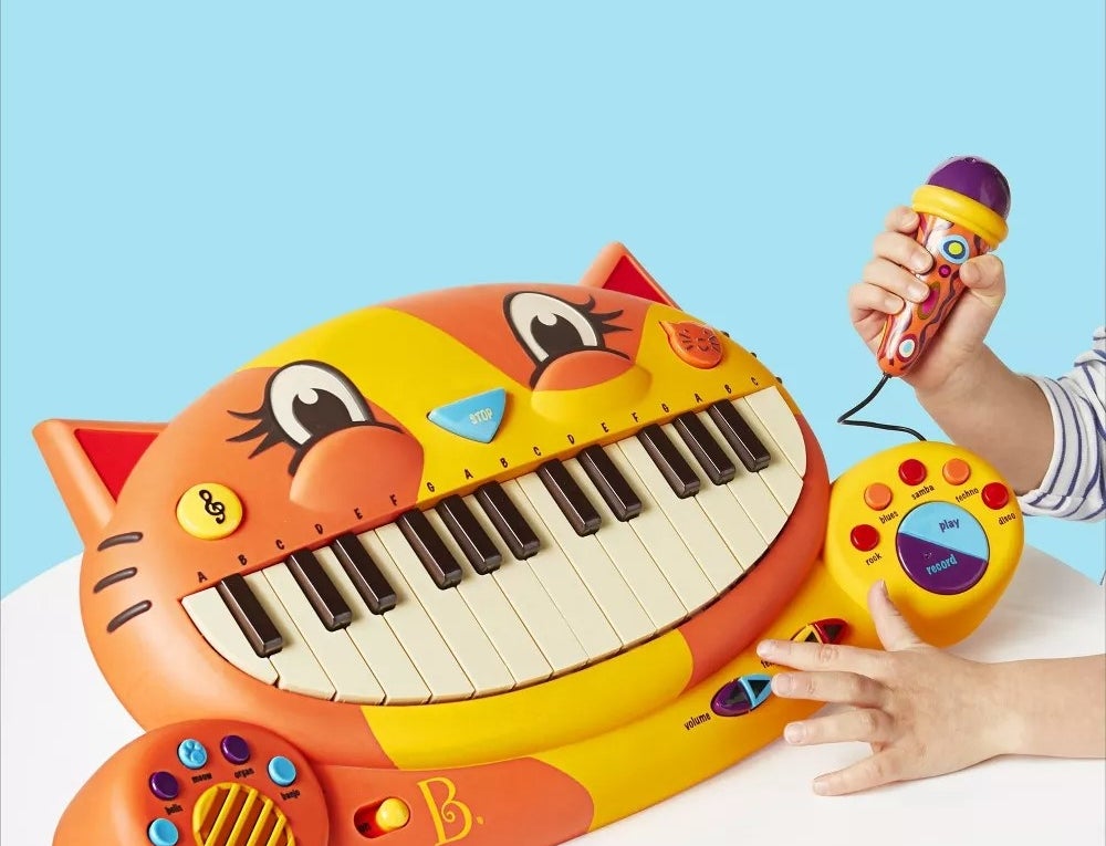 Orange and yellow piano toy shaped like a cat with black and white keys for teeth