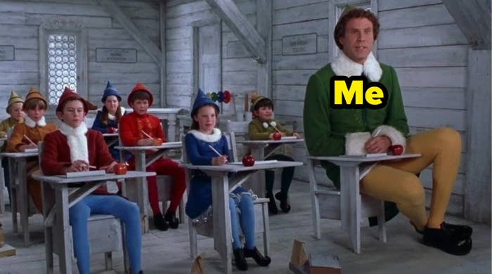grown man in elf costume sits in a classroom of children