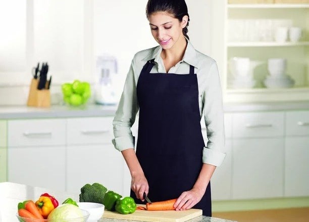model wearing black apron while cutting vegetables
