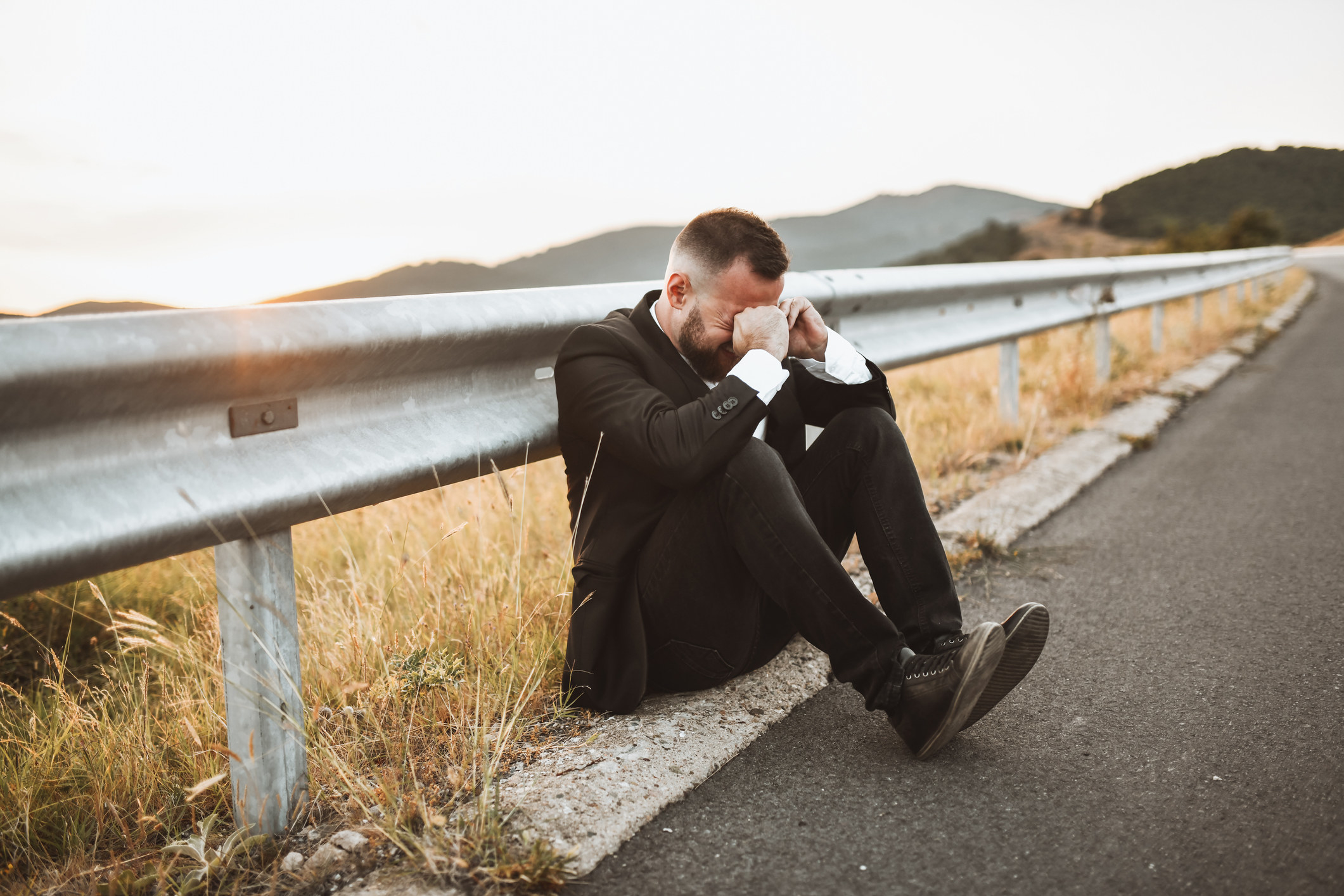 A man in a suit crying by the side of the road