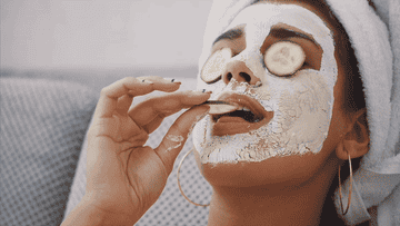 femme avec un masque sur le visage et des concombres sur les yeux