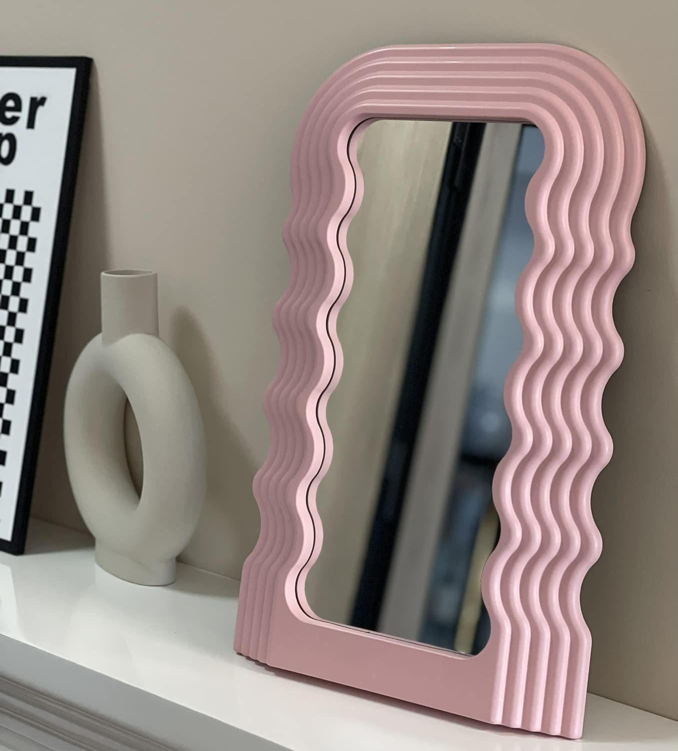 a funky mirror with a wavy frame leaning up against a wall