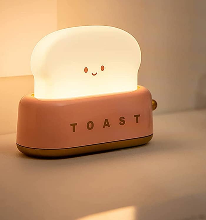 a tiny lamp shaped like a piece of toast coming out of a toaster with a little smiley face