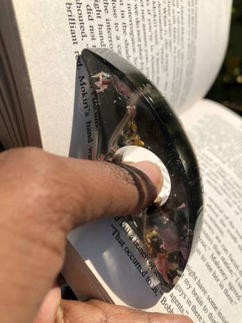 a person holding the colorful page holder between book pages