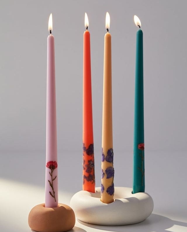 four candles with dried flowers pressed into the ends of each
