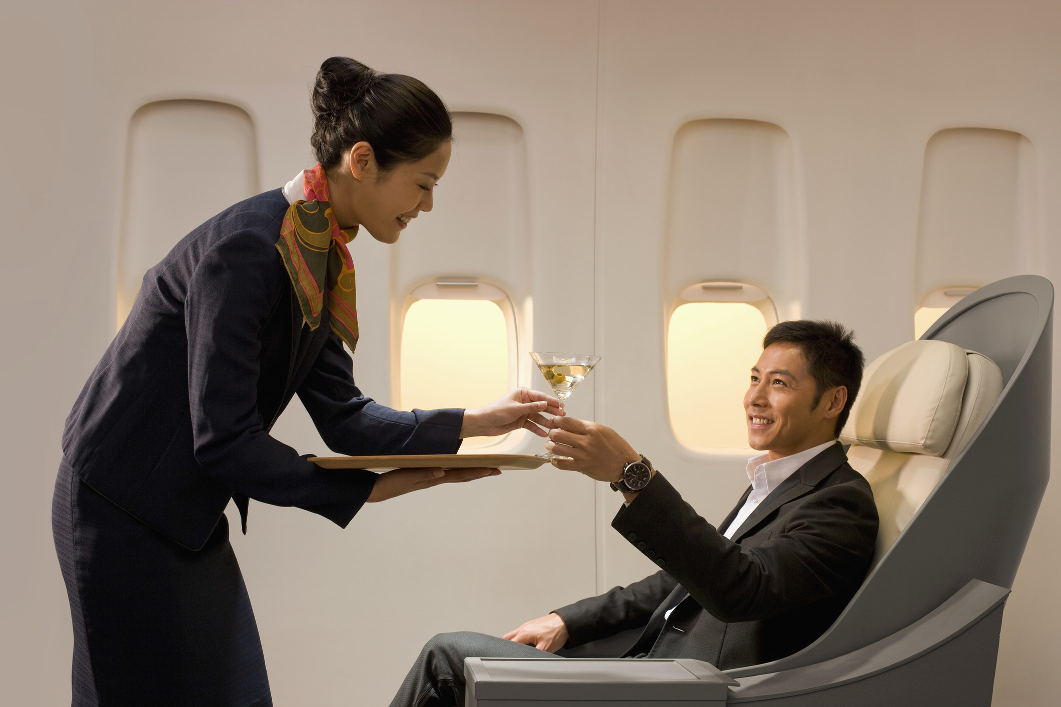 A flight attendant handing a man a drink