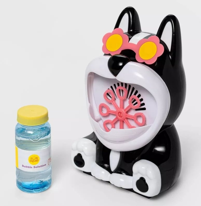 A plastic black and white dog with a bubble maker in its open mouth and a jar of bubble solution