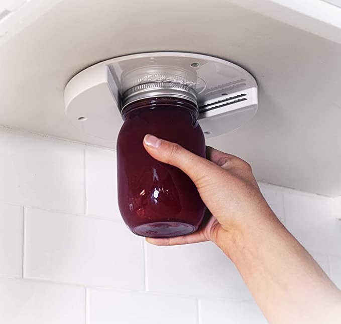 Model&#x27;s hand places a jar into the under-the-counter jar opener