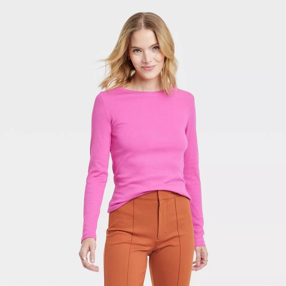 A model wearing the long-sleeve top in pink with orange pants