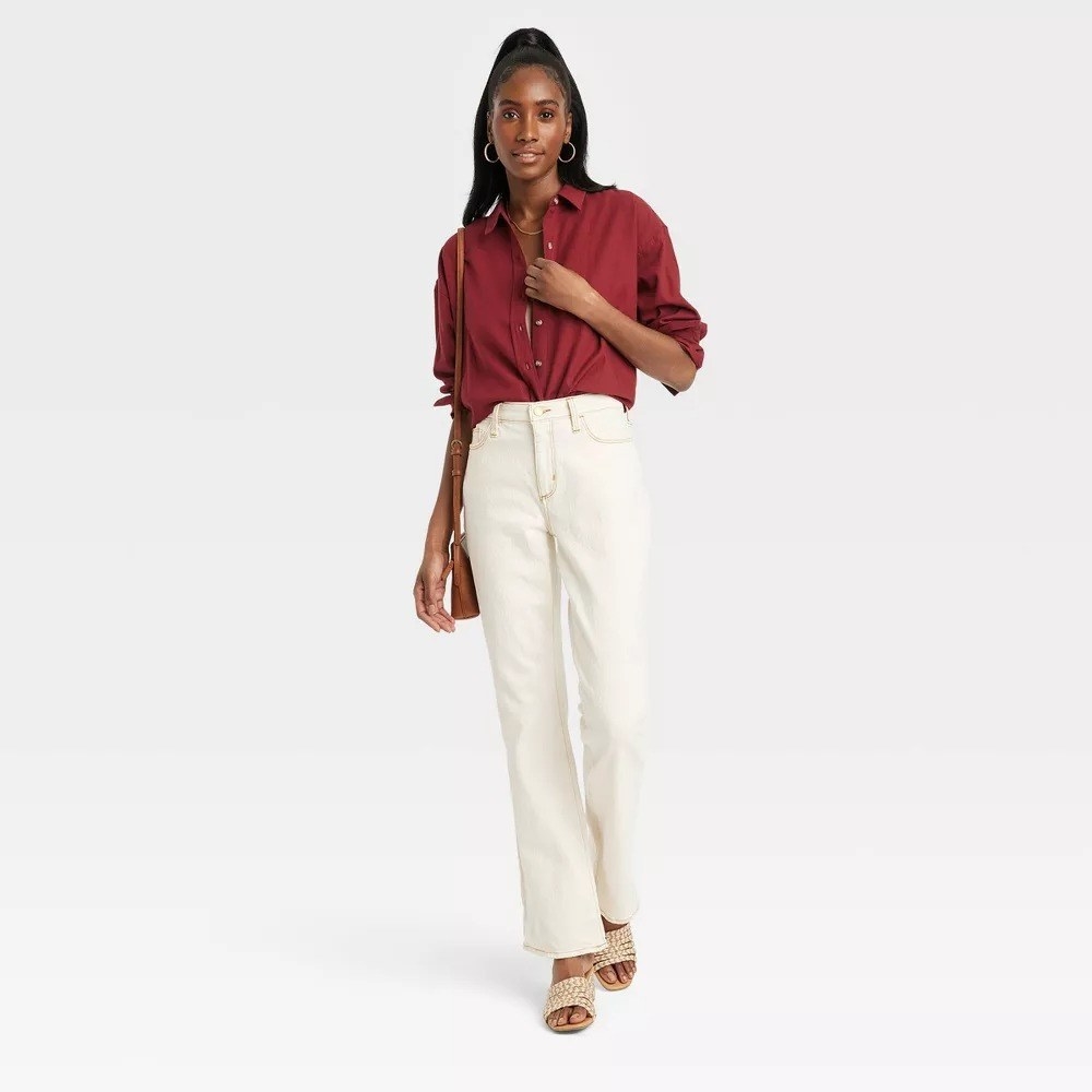 A model wearing the shirt in deep red with white jeans