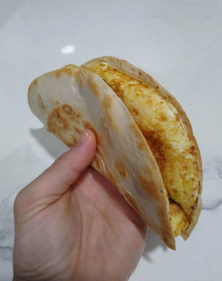 A hand holding an egg quesadilla