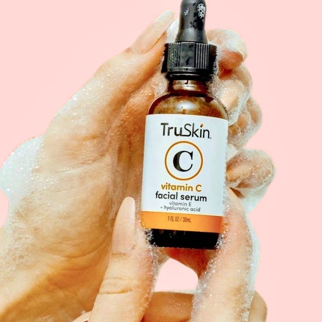 foamy, soapy hands holding the bottle of serum