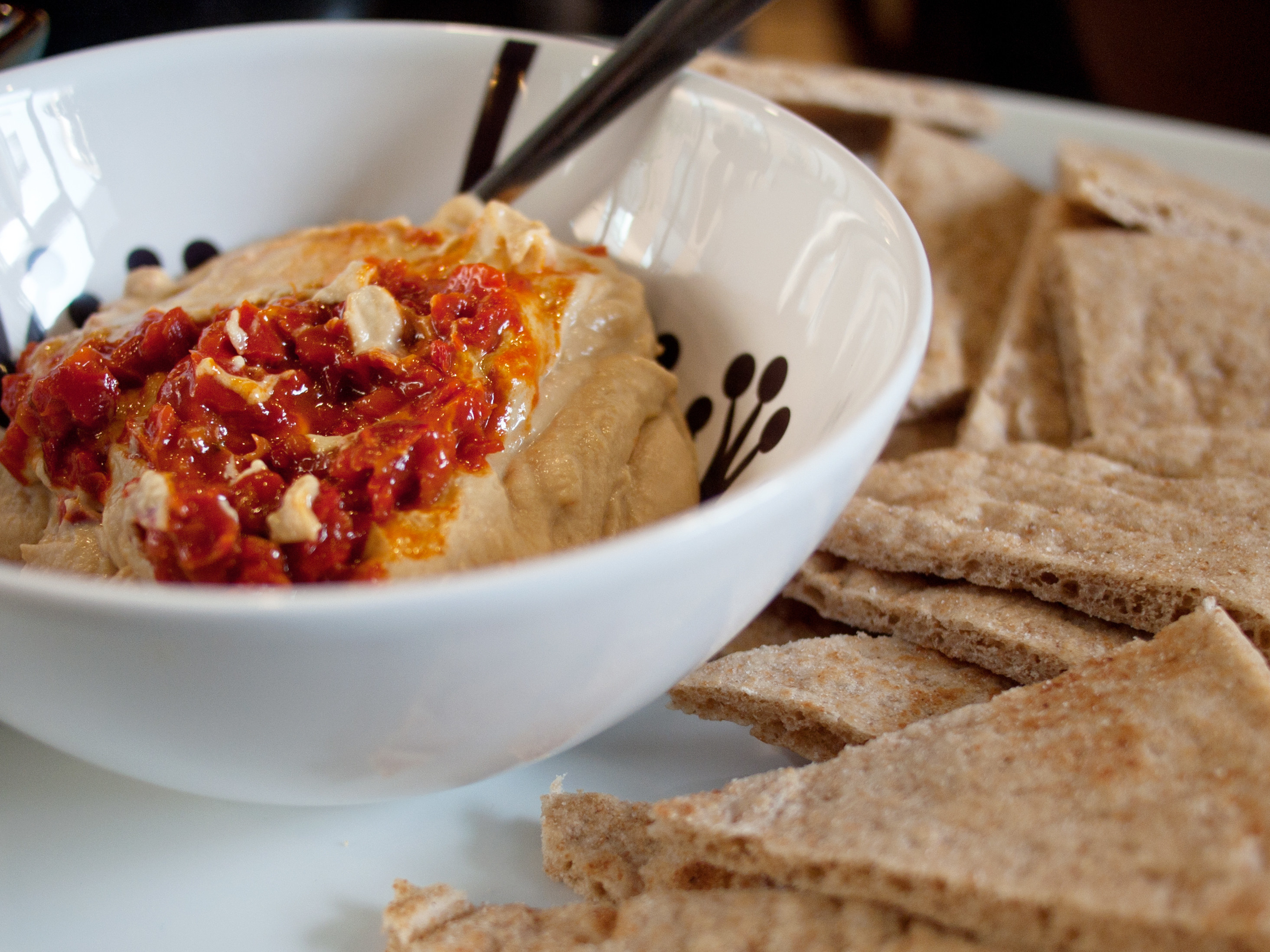 A bowl of spicy hummus and pita