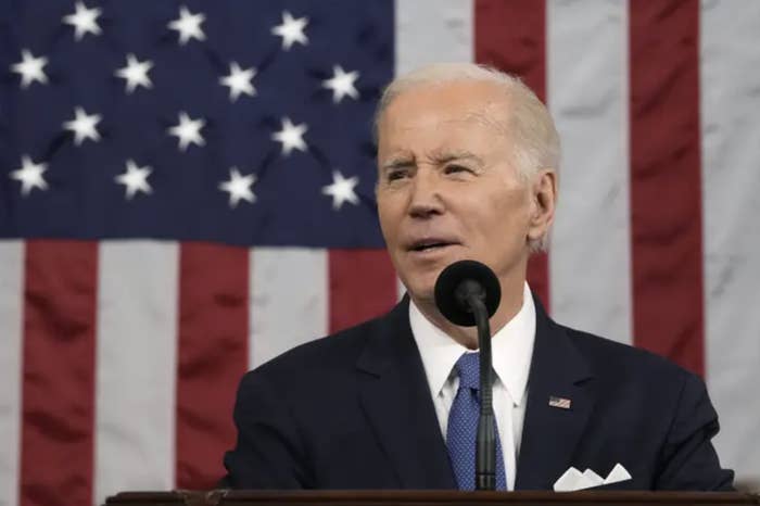 Biden gives a speech at a podium in front of an american flag