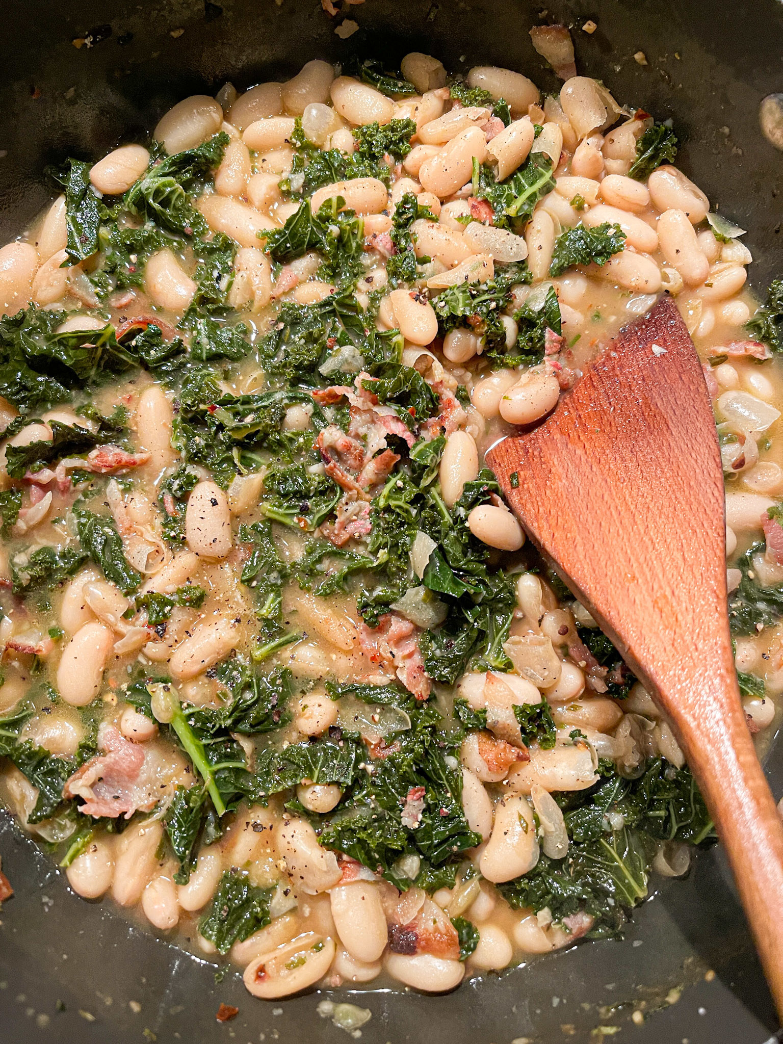 skillet filled with white beans, broth, and plenty of kale