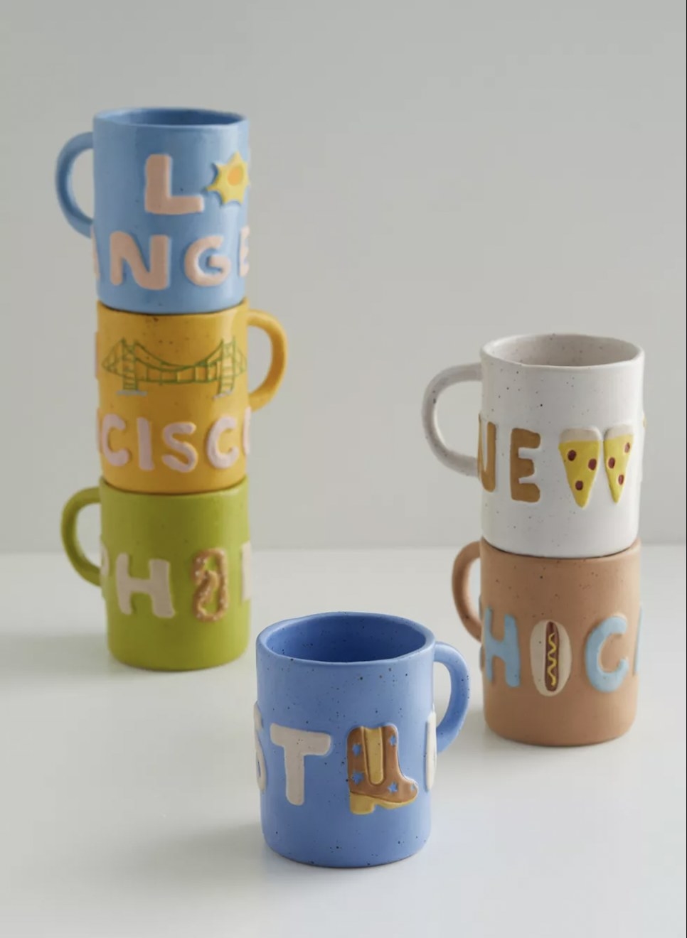 Six mugs in different colors with different city names on them