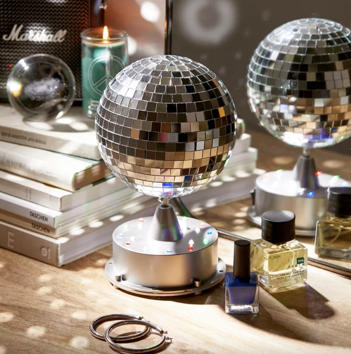 A disco ball speaker by two nail polish bottles and a stack of books