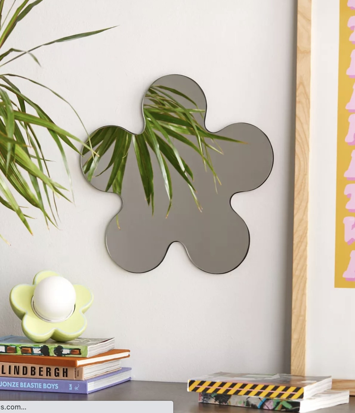 A  flower shaped mirror hung next to a flower shaped lamp