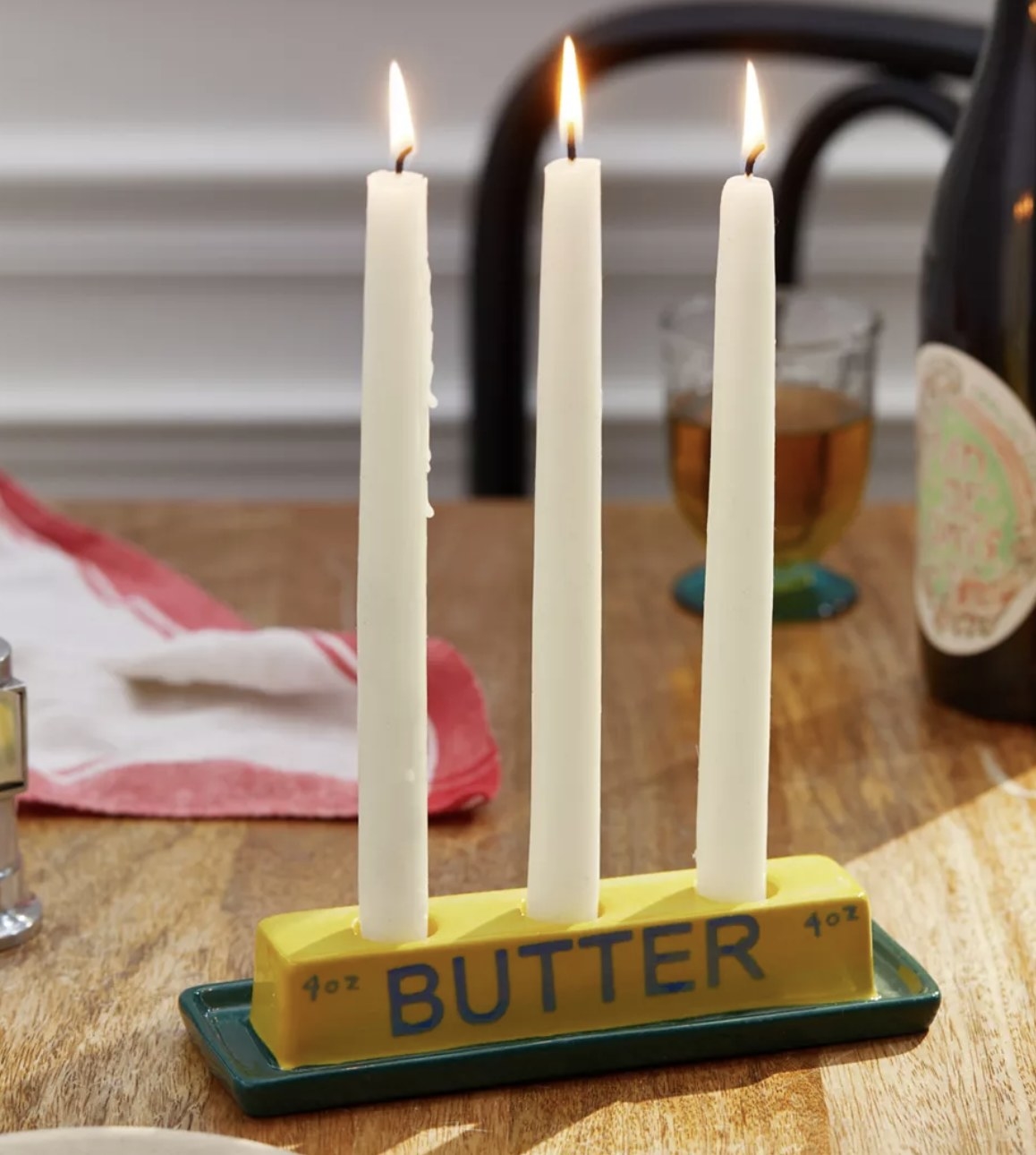 A candle stick holder shaped like a stick of butter holding three candles