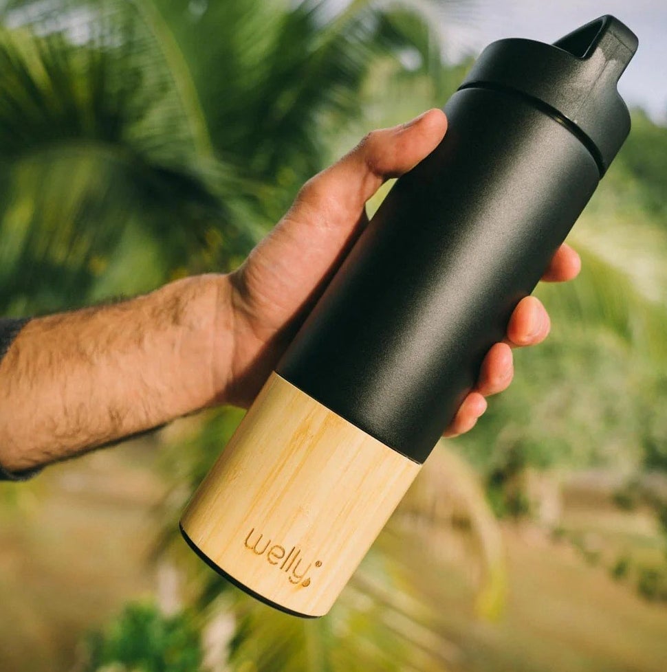 a model holding a black water bottle with a bamboo wood bottom