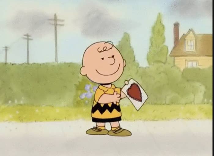 charlie brown holding a card with a red heart on it