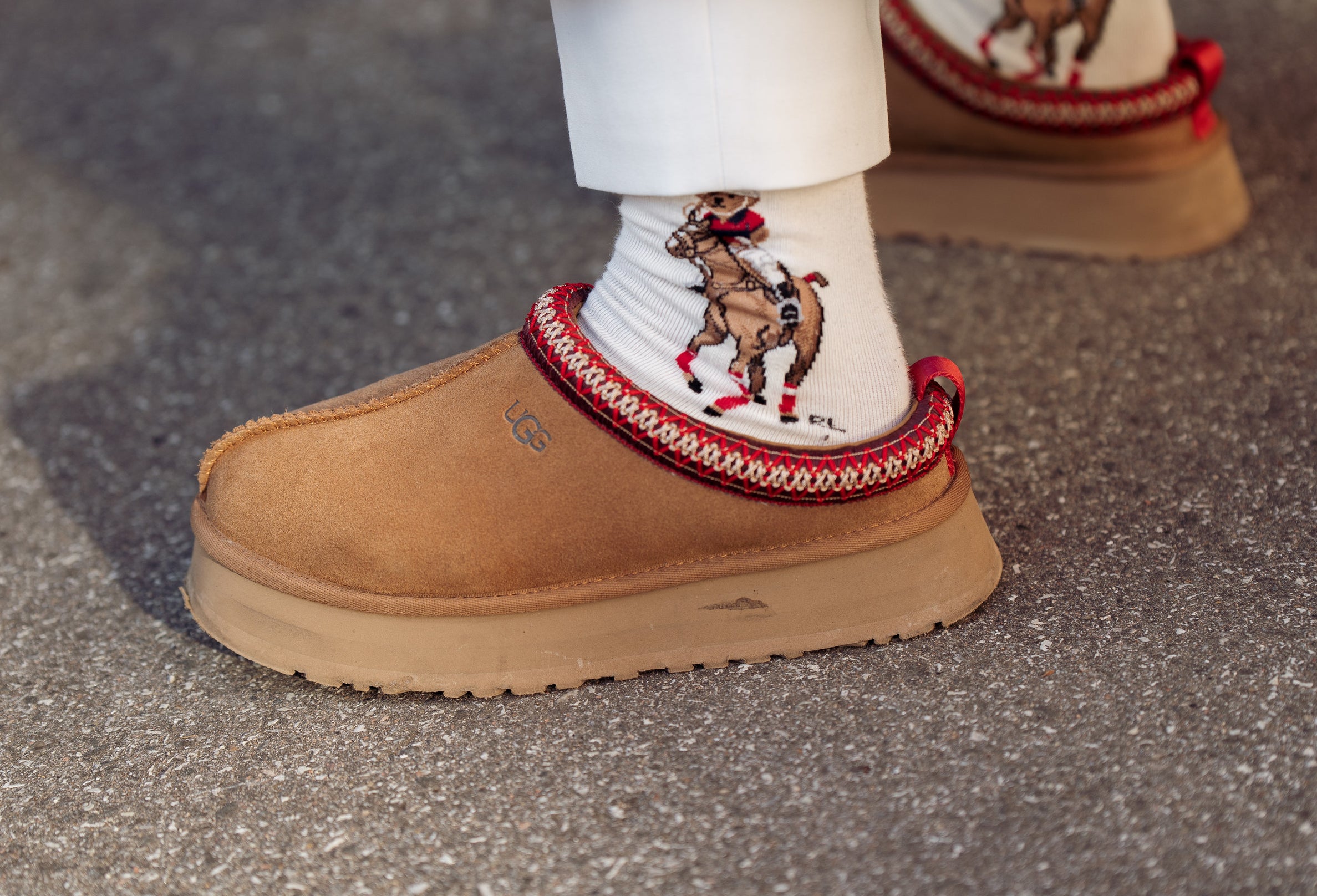 Close-up of somewhere wearing brown ugg slipper shoes with a red trim