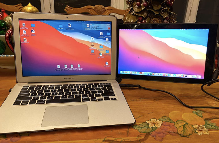 A reviewer's laptop with a small black monitor attached to the existing monitor on a desk