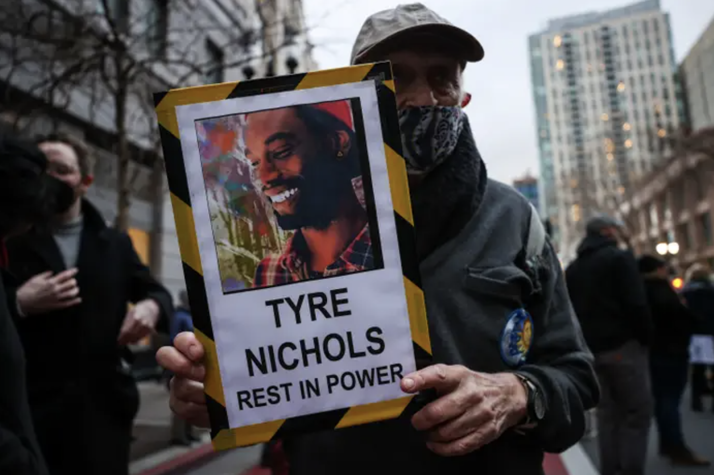 A man holds up a sign with a photo of Tyre Nichols that reads, &quot;Tyre Nichols rest in power&quot;