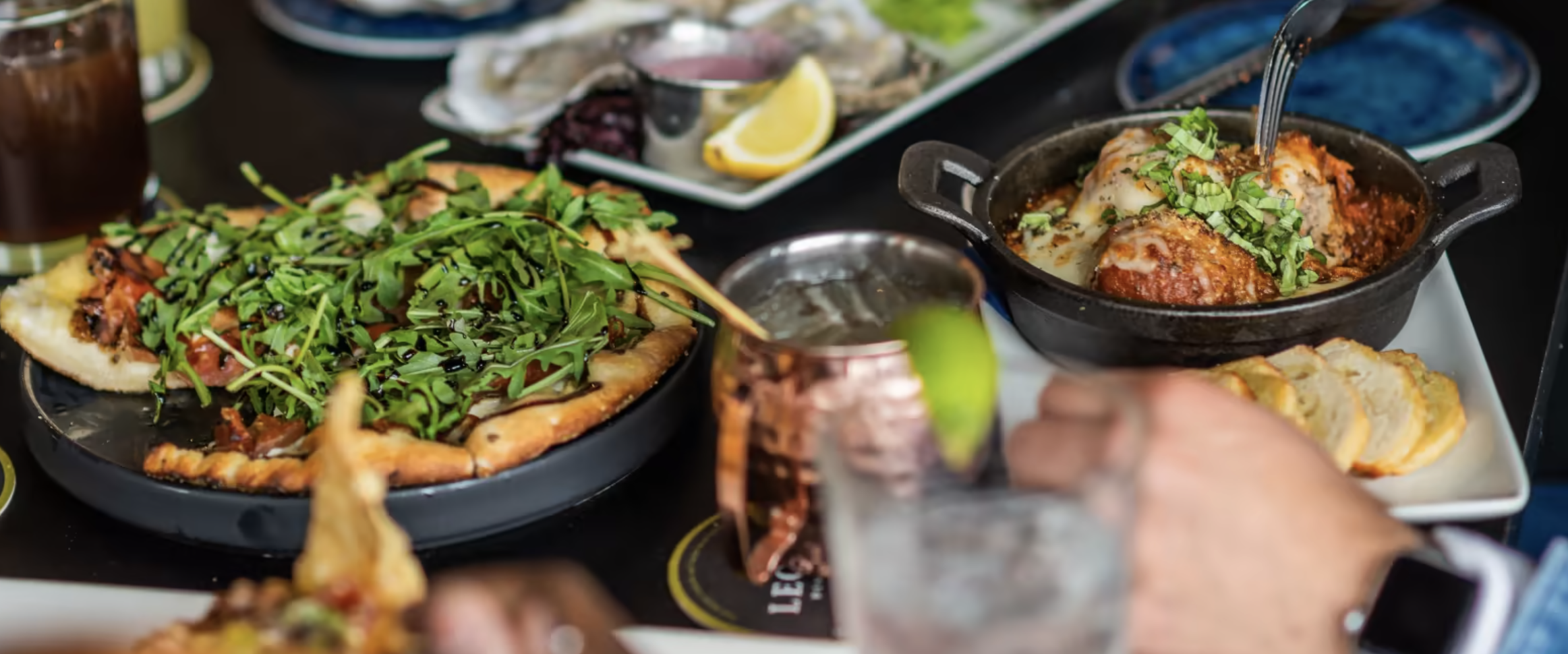 A table with moscow mule cups, pizza and meatballs in a skillet