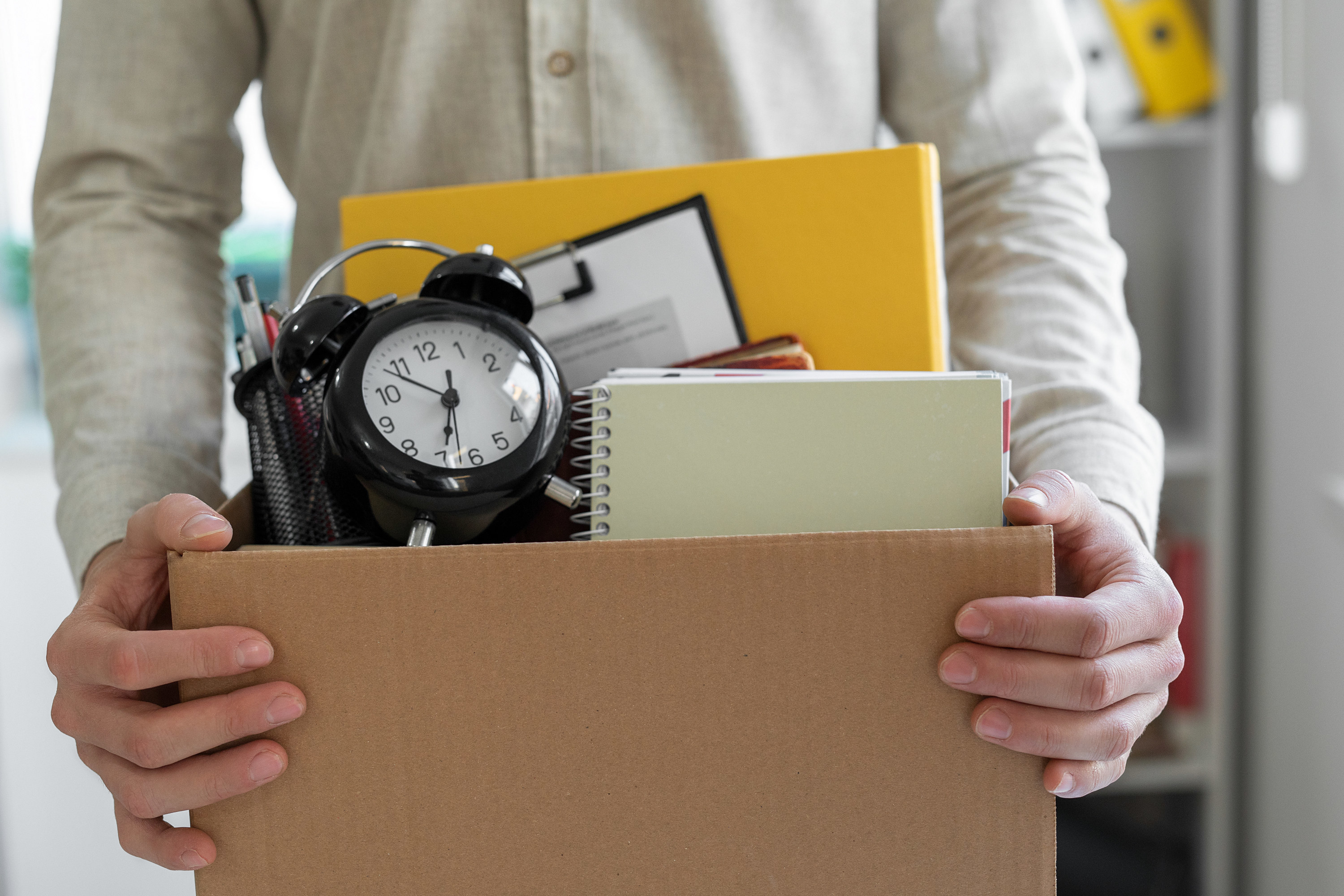 person holding their things in a box after being laid off