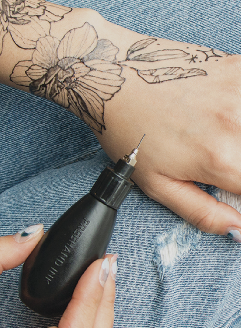 person using the bottle to draw a design on their arm