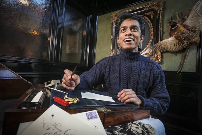 Rajiv smiles while sitting at a desk