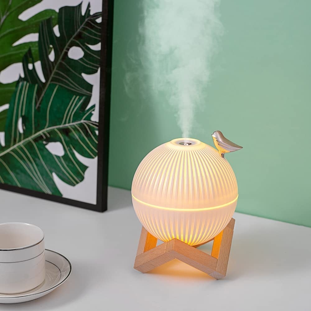 a mini humidifier with a little bird perched on it on a desk