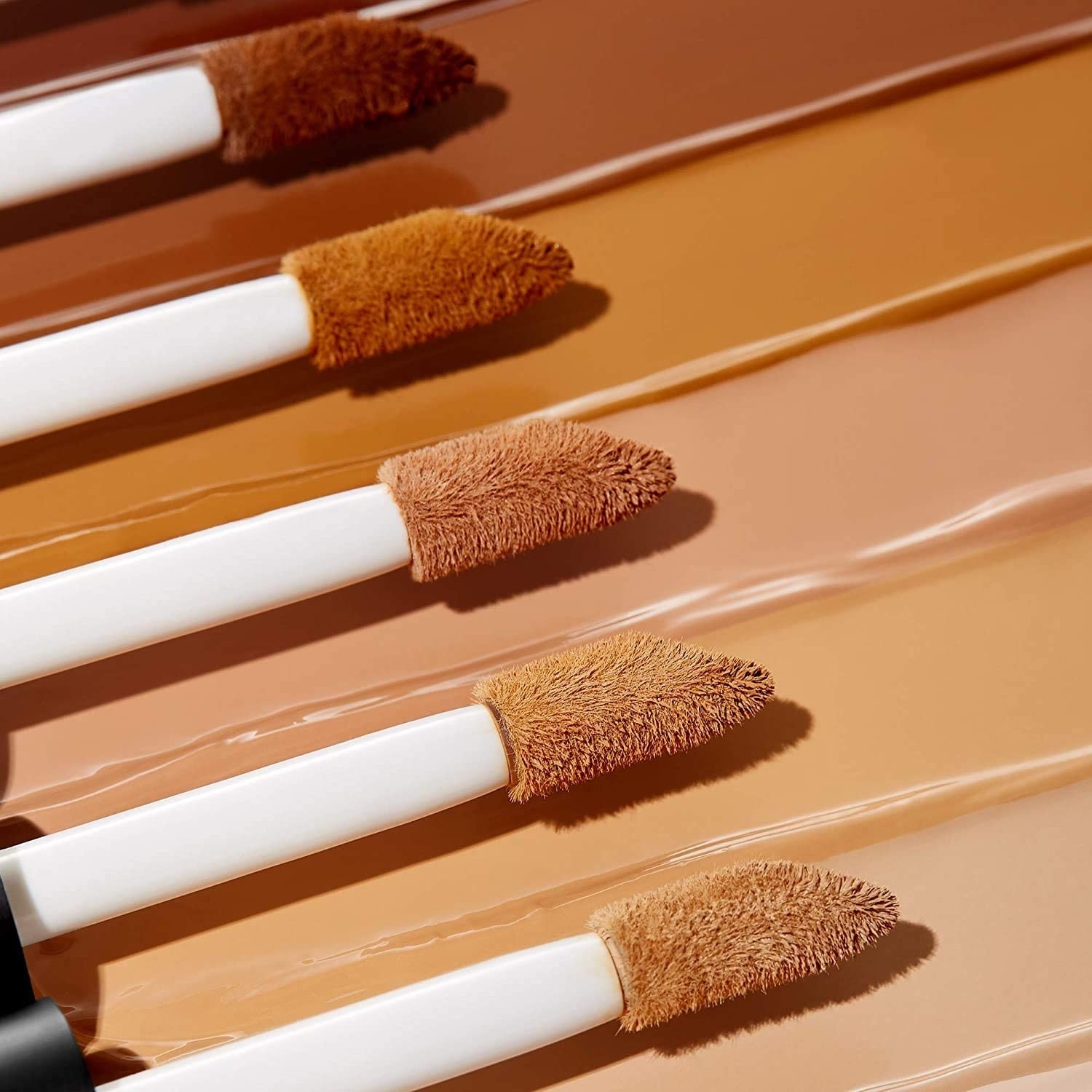 five different shades of concealer underneath their respective brushes