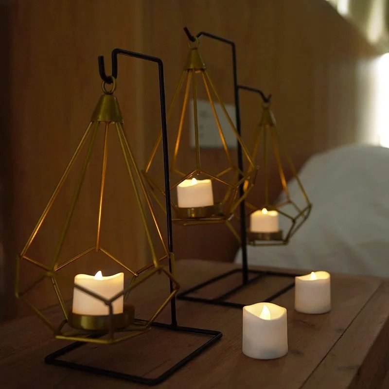 Flameless white candles on table and in geometric bronze candle holders