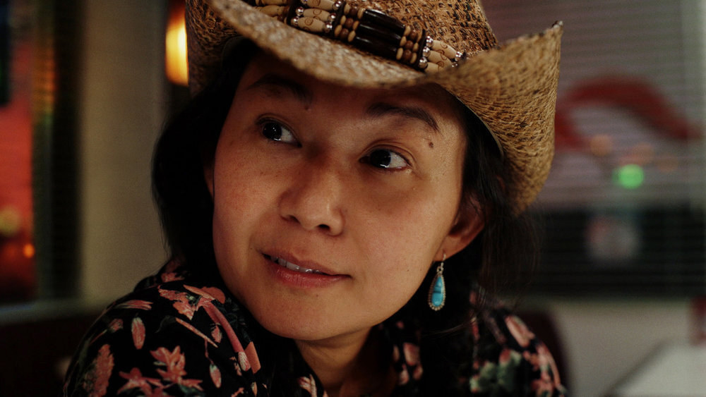 A woman in a cowboy hat engages in conversation at a diner