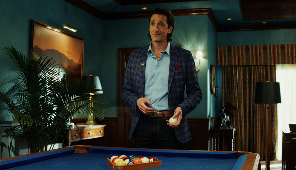 A sharp-dressed casino executive stands by a pool table in a spacious room