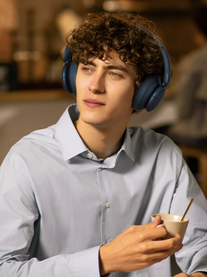 person holding a mug with the headphones on