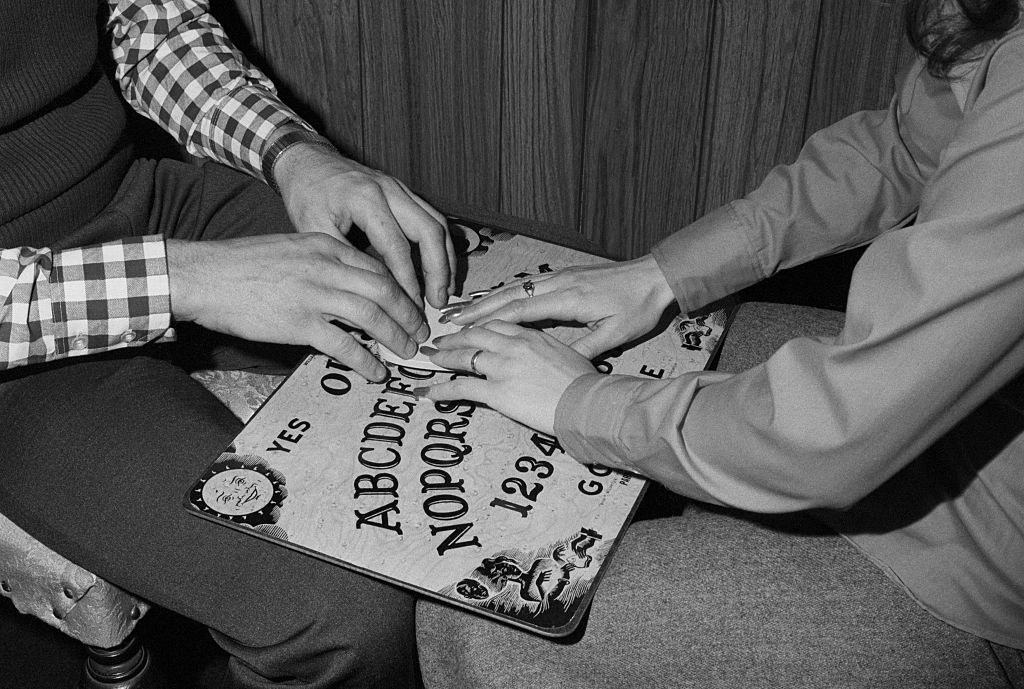 Man and woman with hands on a ouija board