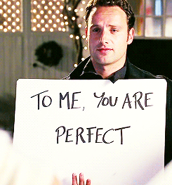 man holds up a poster that says &quot;to me, you are perfect&quot;