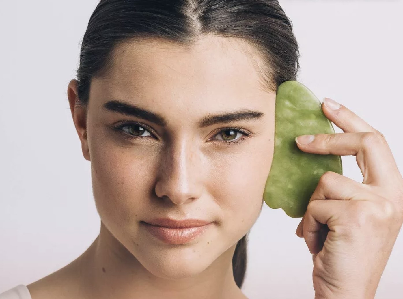 a person using the gua sha tool on their face