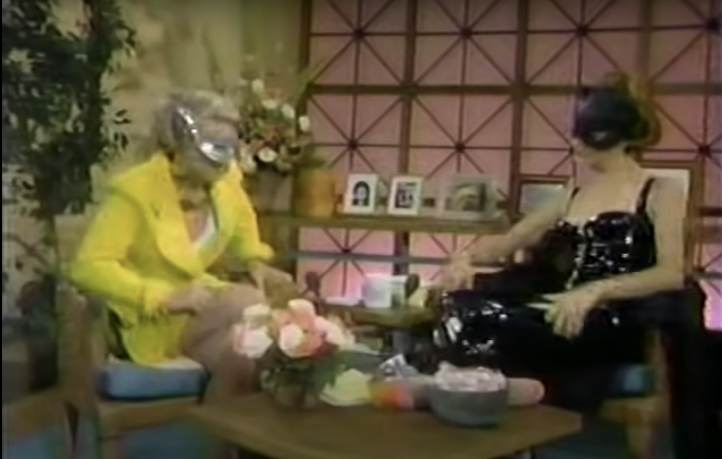two women sitting wearing cat masks