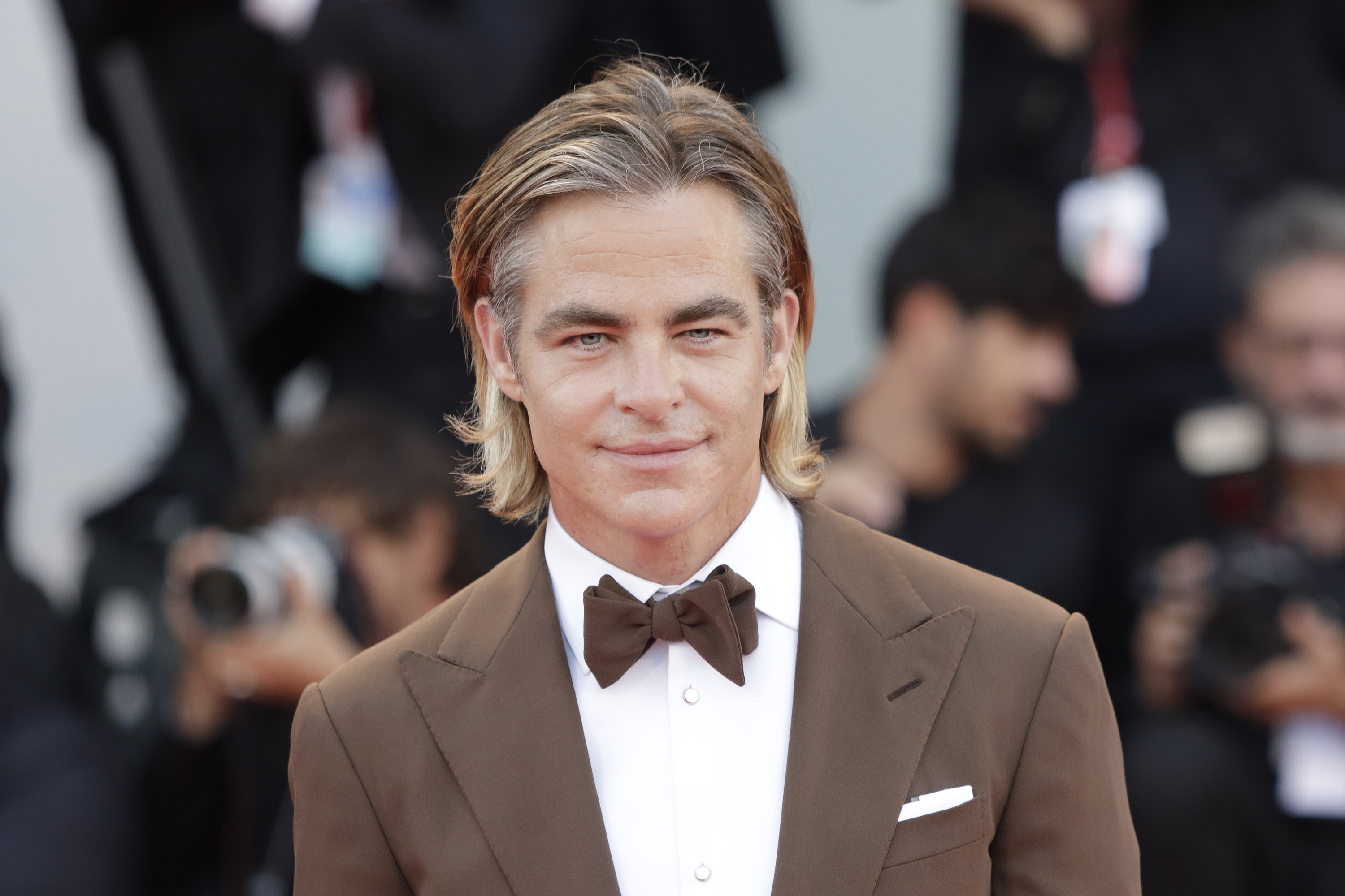 A clean-shaven Chris smiles as he poses for photographers at a red carpet premiere